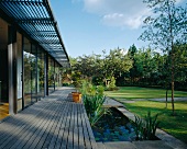 Wooden terrace with adjacent pond in garden of contemporary house