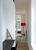 Modern office niche and view through narrow opening to standard lamp in minimalistic room