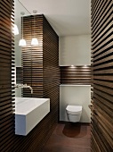 Dark wooden slatted cladding on walls in designer bathroom