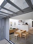 View of dining area with classic chairs and a modern kitchen through open sliding terrace door