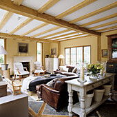 Living room with wooden beamed ceiling and fireplace, leather sofa and leather armchair