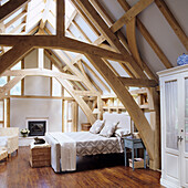 Attic bedroom with exposed wooden beams and light-coloured interior