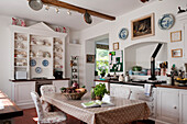 Country-style kitchen with white wooden units and shelves with crockery