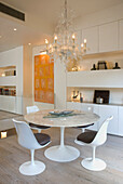 Runder Marmortisch mit weißen Designerstühlen und Kronleuchter im modernen Esszimmer