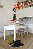 White kitchen with orange chandelier and transparent chairs