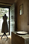 Vintage dress on dressmaker's dummy next to old wooden chest in rustic room