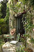 Idyllic seating area with rose vines and vintage furniture in the garden