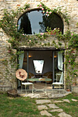 Stone house with rose garland, patio door and metal garden table set