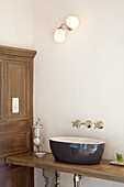 Wooden washbasin with round ceramic bowl in the bathroom