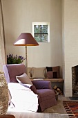 Comfortable reading chair next to standard lamp and bench against wall in simple living room