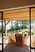 View of set table in rural garden through open terrace doors