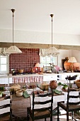 Vintage pendant lamps with fabric lampshades above set table and antique wooden chairs in rustic kitchen