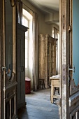 View of antique, rustic, glass-fronted cupboard though open interior doors in grand, old country house