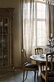 Rococo-style chairs at dining table in front of terrace doors in rustic interior