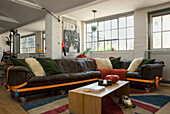 Loft living room with leather couch, colourful cushions and industrial windows