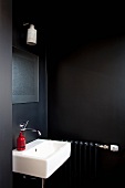 Roter Seifenspender auf Waschbecken in schwarz getöntem Bad