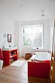 Helles Badezimmer mit freistehender Badewanne in rot-weißen Farbakzenten