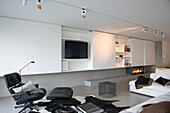 Minimalistisches Wohnzimmer mit Einbauschränken, modernem Kamin und Lounge Chair