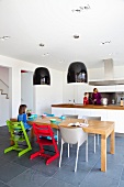 Open-plan kitchen with solid wooden table and brightly coloured children's chairs