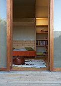 View from outside of living room with wooden bench and fur rug