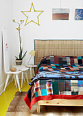 Bed with chequered throw, patterned blanket and decorative star on the wall