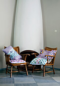 Two armchairs with patterned cushions in front of a white fireplace