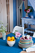 Crockery and flower arrangement on wooden table with blue table runner