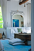 Living room with antique wooden coffee table and white sofa in front of large mirror