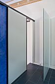 Modern bathroom with partition of sliding panels and dark grey slate floor
