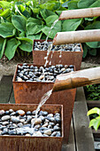 Watercourse with bamboo channels and containers with stones in the garden