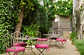 Seating area with metal furniture and pink cushions in the inner courtyard