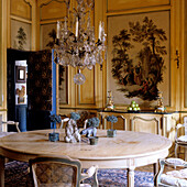 Round wooden table and crystal chandelier in a classic dining room