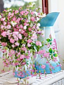 Pink flowers in enamel jug with floral motifs