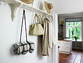 White coat rack with hooks in foyer and view into kitchen