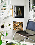 Kaminofen mit Holzvorrat in modernem Wohnraum mit Freischwinger-Stuhl