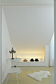 Minimalist room with white interior, sloping ceiling and indirect lighting