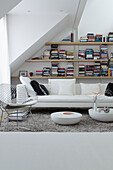 Modern living room in white with bookshelves under a sloping roof