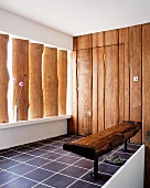 Rustic bench and vertical wooden planks on walls and in window recess