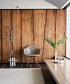 Classic chair with grey plastic shell seat in front of rustic wooden wall