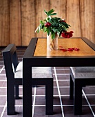Tisch mit schwarzem Rahmen und heller Holzplatte mit Blumenvase und passendem Stuhl