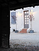 View of house and front door with wall lamps through open barn door