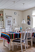 Bright dining area with white wooden furniture and colorful tablecloth