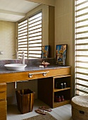 Grosser Badezimmerspiegel über Waschschüssel auf Waschtisch aus Holz und Stein mit Handtuchstange und Schuhregal