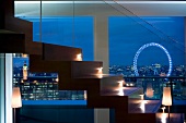 Illuminated stairs in front of large windows with evening view of London