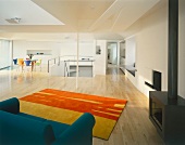 Offener minimalistischer Wohnraum mit Loungeecke vor Kaminofen