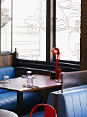 Sitzplatz in englischem Lokal - Lounge-Nischen mit Lederbänken vor Fenster mit gezeichnetem Vespa Motiv