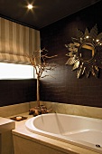 Sonnenförmiger Spiegel über der Badewanne in Badezimmer mit dunkelbraunen Wänden