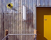 Ausschnitt einer Hausfassade mit Kunststoffverkleidung und gelber Eingangstür