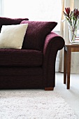 Dark red sofa with scatter cushions and side table with flowers