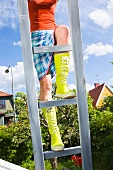 Woman climbing ladder in garden